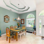 A bright dining area with custom-painted chairs and table, adorned with beach-themed artwork, offering a cheerful space for meals.