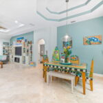 Spacious living and dining area in a St. Augustine vacation rental featuring colorful, hand-painted furniture, a cozy seating area, and unique tropical decor.